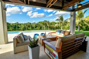 eine Außenterrasse mit Sofas und einem Pool in der Unterkunft VILLA HERMOSA CHEF MAiD POOL JACUZZI GOLF CART in La Romana