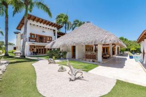 a house with a straw roof and a grass yard at YARARI 17 PRIVATE RETREAT W POOL JACUZZI MAiD in Punta Cana