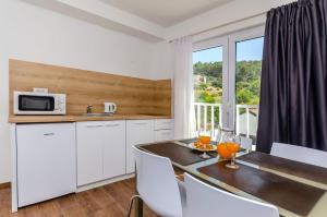 a kitchen with a table with chairs and a microwave at Apartments Villa Niko in Trogir
