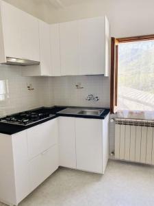 uma cozinha com armários brancos, uma pia e uma janela em Un Tuffo nel Mare em Levanto