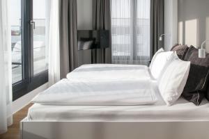 a bed with white sheets and pillows in a room at AMANO HOME Apartments in Berlin