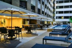a hotel patio with tables and chairs and a swimming pool at Nomar VI - Gold Flat in João Pessoa