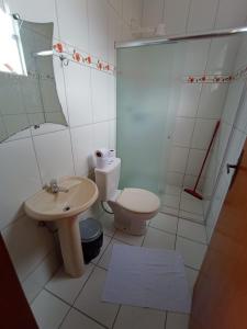 a bathroom with a toilet and a sink and a shower at Pousada Lirio do Vale in Cachoeira Paulista