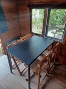 einen schwarzen Tisch und Stühle in einem Zimmer mit Fenstern in der Unterkunft Trekkershut I Ideale uitvalsbasis op de Veluwe in Epe