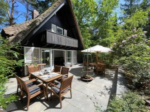 a patio with a table and chairs and an umbrella at Ferienhaus mit Teich auf 16.000m² in der Natur in Hermannsburg