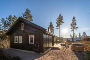 une petite cabine dans les bois avec le soleil en arrière-plan dans l'établissement Gezellige woning met hottub en sauna, à Vradal