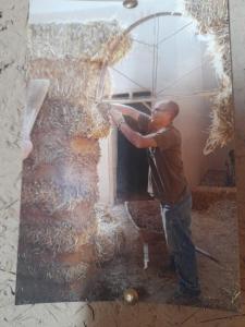 a man is cutting up hay on a wall at back to original home in Merzouga