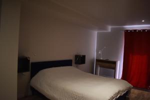 a bedroom with a bed with a red curtain at La Cour de l'Olivier in Lussas