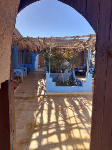 a view through an archway of a patio with white buildings at back to original home in Merzouga