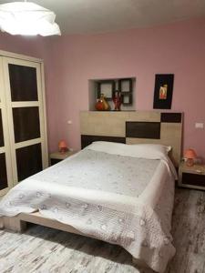 アックイ・テルメにあるVilla Gioiaのピンクの壁のベッドルーム1室(大型ベッド1台付)