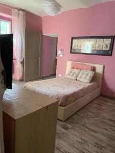 um quarto rosa com uma cama e uma mesa em Villa Gioia em Acqui Terme