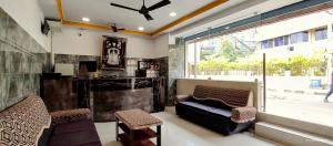 - un salon avec un canapé, des chaises et une fenêtre dans l'établissement Sarovara Deluxe Rooms, à Chennai