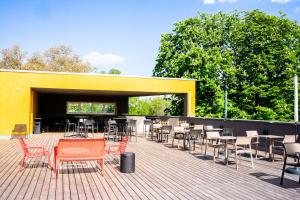 eine Terrasse mit Stühlen und Tischen sowie ein gelbes Gebäude in der Unterkunft The Base Berlin ONE in Berlin