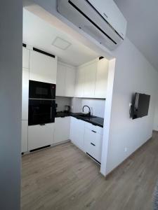 - une cuisine blanche avec des armoires blanches et des appareils noirs dans l'établissement Apartament nad Iławką, à Iława