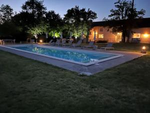 una piscina en un patio por la noche en Ferme Binel à Ronsac, en Aigrefeuille