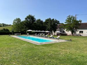 una piscina en un patio con sillas y sombrillas en Ferme Binel à Ronsac, en Aigrefeuille