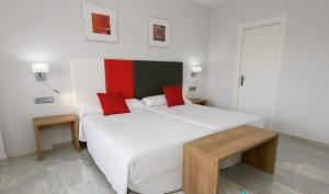 a bedroom with a large white bed with red pillows at First Flatotel International in Benalmádena