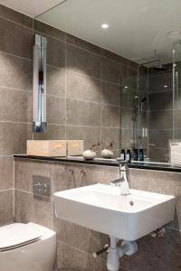 a bathroom with a sink and a toilet and a mirror at The Wood Hotel by Elite, Spa & Resort in Skellefteå