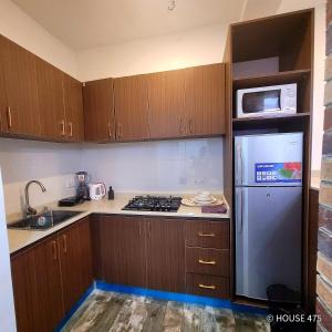 a small kitchen with wooden cabinets and a refrigerator at House 475 Apartments. in Abuja