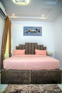 a bedroom with a large bed with pink sheets at House 475 Apartments. in Abuja