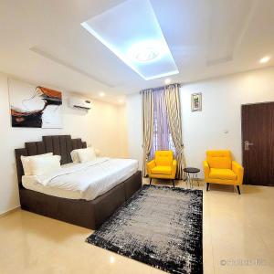 a bedroom with a bed and two yellow chairs at House 475 Apartments. in Abuja