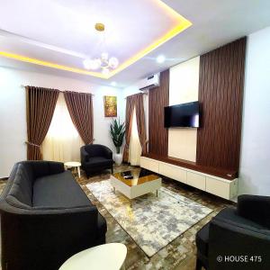 a living room with a couch and a tv at House 475 Apartments. in Abuja