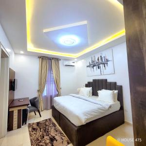 a bedroom with a bed and a desk and a chair at House 475 Apartments. in Abuja