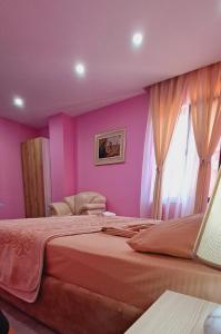 a pink bedroom with a large bed and a window at CityCenterHotel Shkoder in Shkodër