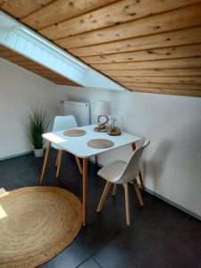 uma mesa branca e cadeiras num quarto com tecto em madeira em Möwenkoje -klimatisiert- em Alsum