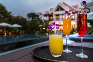 Angkor Privilege Resort & Spa في سيام ريب: اثنين من المشروبات على طاولة بجوار حمام السباحة