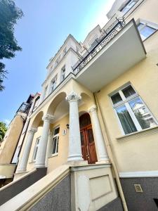 een geel huis met zuilen en een rode deur bij Agapella Apartamenty- Apartament Helska 3 - 250m form the beach in Sopot