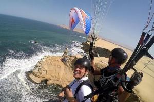 two men in helmets are riding a kite over the ocean at HOTEL LUCERO PARACAS in Paracas