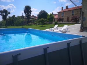 a swimming pool with two chairs and a house at Casa Marisa in Teo