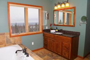 a bathroom with a tub and a sink and two windows at MyLutsen in Lutsen