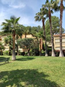 a park with palm trees in front of a building at LE VALLON DU ROY in Sanary-sur-Mer