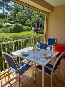 a white table and chairs on a porch with a view of a yard at LE VALLON DU ROY in Sanary-sur-Mer