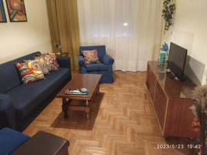 ein Wohnzimmer mit blauen Sofas und einem Couchtisch in der Unterkunft Anna's flat in Volos