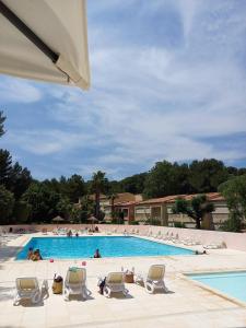 una gran piscina con sillas y gente en ella en LE VALLON DU ROY, en Sanary-sur-Mer
