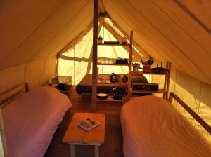 um quarto com duas camas numa tenda em Tente Trappeur Ada, Au jardin de la Vouivre em Saint-Vincent-en-Bresse