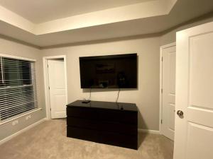 sala de estar con cómoda negra y TV de pantalla plana en Brand NEW HOME mins to airport en Atlanta