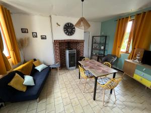 salon z kanapą i stołem w obiekcie Le logis d’Aimé w mieście Saint-Blimont
