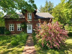 uma casa de tijolos com uma porta branca e algumas flores cor-de-rosa em Alte Stellmacherei Langenhorn em Langenhorn