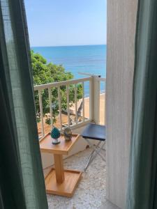 uma varanda com uma mesa e uma cadeira e a praia em MARE CELESTE APPARTAMENTO em Sciacca