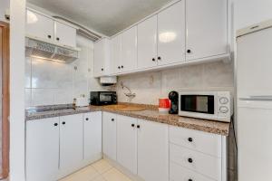 una cucina bianca con armadi bianchi e forno a microonde di Torres del Sol Beach Front Apartment PH06 a Los Cristianos