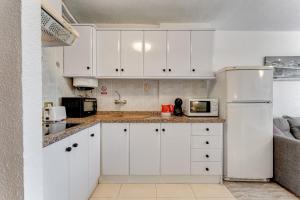 una cucina con armadietti bianchi e frigorifero bianco di Torres del Sol Beach Front Apartment PH06 a Los Cristianos