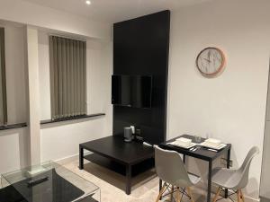 uma sala de estar com uma mesa e um relógio na parede em Augustus House 1 Bedroom Apollo Suite em Bradford