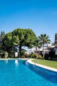 a large blue swimming pool with trees in the background at Golden Mile Designer Penthouse in Marbella