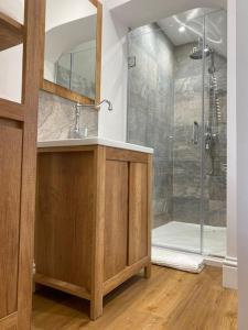 a bathroom with a shower with a sink and a mirror at Luxury Self Catering Studio with vaulted ceiling in Ockley