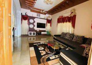 un soggiorno con un divano nero e una TV di His Grace Holiday Home - Nr to Malpe Beach a Udupi