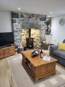 a living room with a stone fireplace and a coffee table at Amazing coastal & sunset views in Eryri (Snowdonia) in Llanllyfni